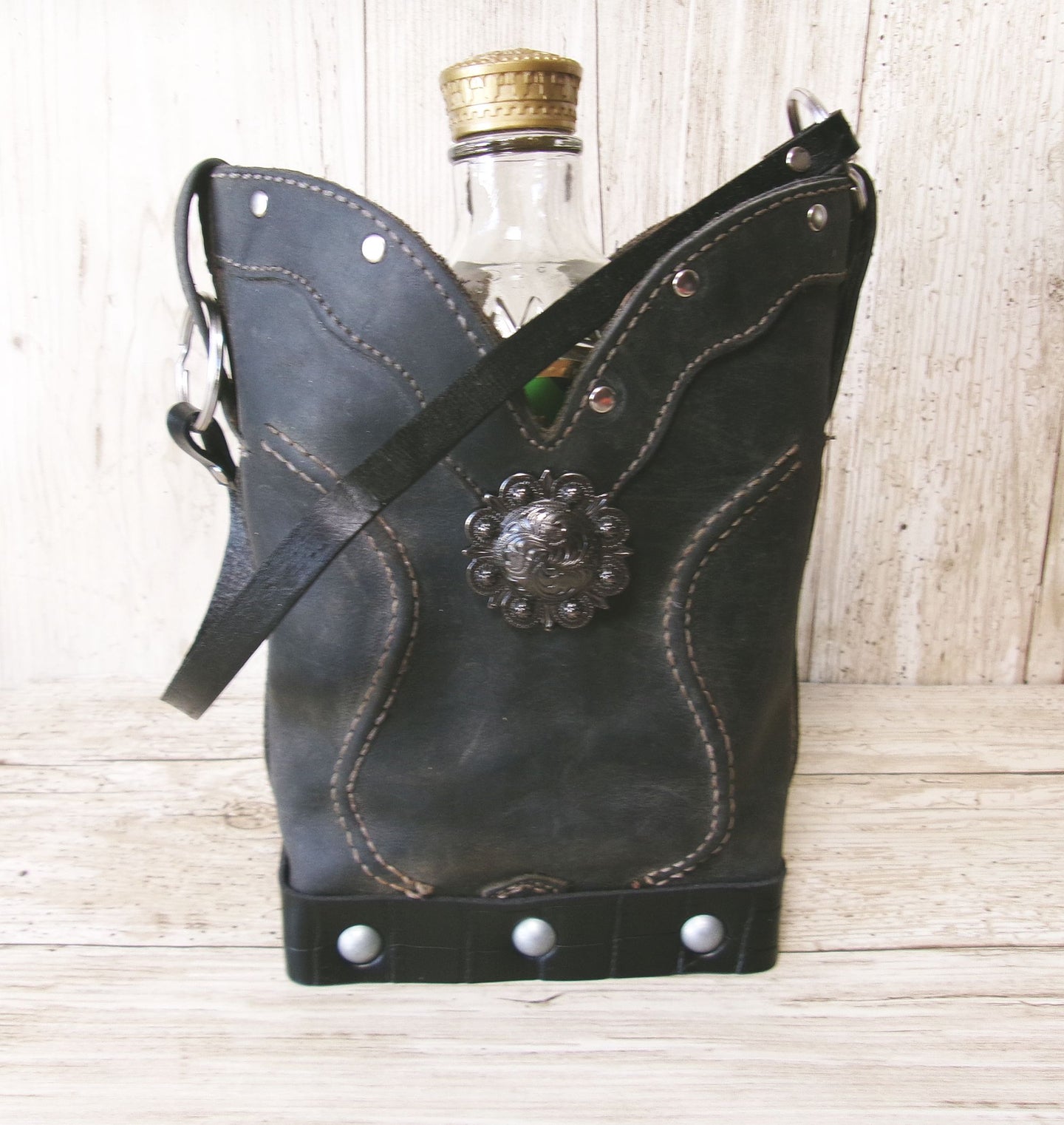 Black leather flask with decorative emblem on a wooden surface